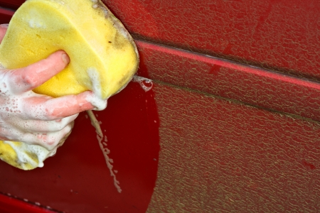 Cleaning the dirty car by hand with a yellow soapy sponge better than automatic car washの写真素材