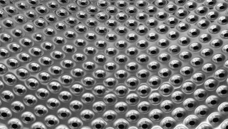 polished metal texture background with punched holes from inside of washing machine drumの写真素材
