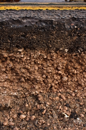 Cut away cross section of a street with exposed soil underneath while maintenance work for utilities company is in progressの写真素材