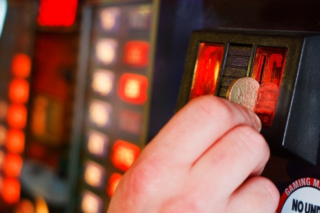Gambler Inserts pound coin into gambling machine at casinoの写真素材