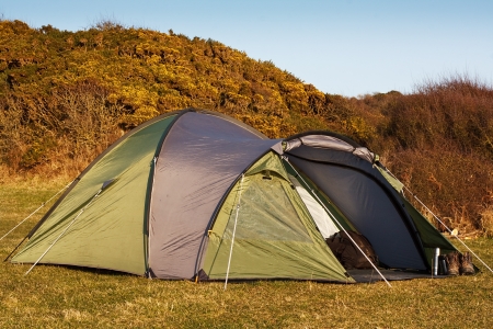 dome tent pitched in field for wild camping in the great outdoors with front flap open showing interiorの写真素材