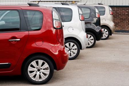 row of new cars for retail sale in a motor dealer yard showing same model in different color choicesの写真素材