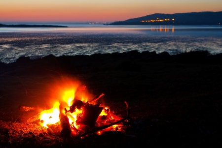 Roaring camp fire of real wood collected at the beach with the coast and sea in the vistaの写真素材