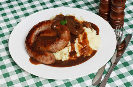 Serving of Traditional Cumberland Sausage with Creamy Mashed Potato and a rich onion gravy, served on a plate in a diner with a green gingham tablecloth の写真素材
