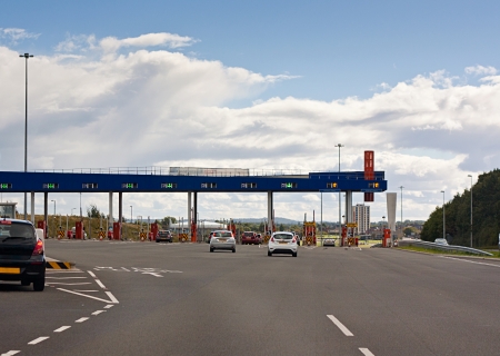 Cars approaching a toll gate, erected to charge drivers for the use of a road and fund maintenance, repair and new transport projects の写真素材