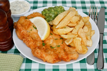 Plate of fish and chips with mushy peas and a slice of lemon on a diner table  A traditional British Seaside Dishの写真素材