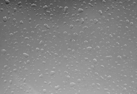 Photo of a window pane with raindrops on symbolising dull wintry weatherの写真素材