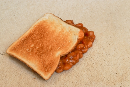 Baked Beans on toast accidentally dropped and creating a carpet stain on beige pile floor coveringの写真素材