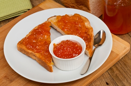 Marmalade fruit preserve on toast on traditional rustic farmhouse breakfast settingの写真素材