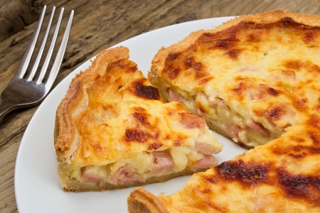 Portion of cheese and bacon flan cut from the quiche lorraine in a rustic traditional farmhouse settingの写真素材