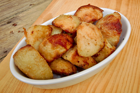 Crispy Roast potatoes in a serving dish against a traditional rustic kitchen tableの写真素材