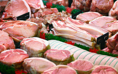 Butchers display counter showing popular cuts of pork including joints, pork chops, belly pork and rolled shoulderの写真素材