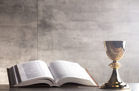 Holy Bible and gold chalice on stone table and backgroundの写真素材