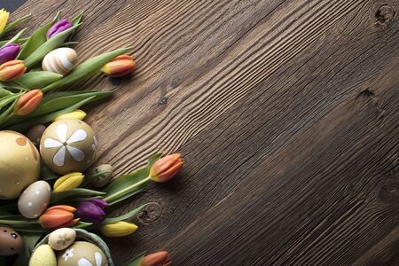 Easter theme. Bouquet of tulips. Easter eggs. Colorful bokeh, place for typography  . Rustic wooden...