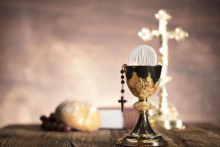 Holy Bible, the cross and gold chalice on wooden table and stone backgroundの写真素材