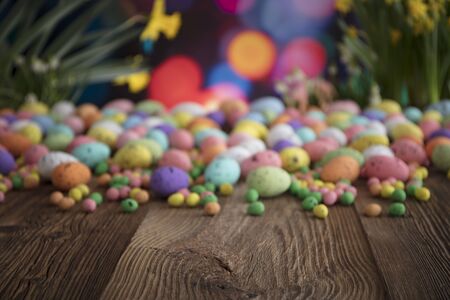 Easter theme. Bouquet of jonquils. Easter eggs in baskets. Colorful bokeh, place for typography  ...