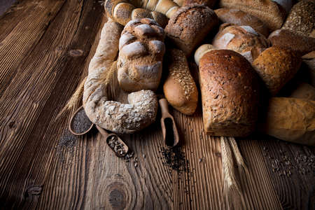 Mixed bread top view shot. Different fresh bread on old wooden table.の写真素材