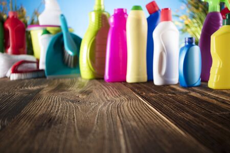Spring cleanup theme. Variety of colorful house cleaning products on a rustic wooden table and blue background.の写真素材