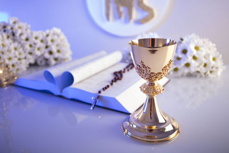First Holy Communion. Catholic religion theme. Crucifix, Bible, bread isolated on white table and...