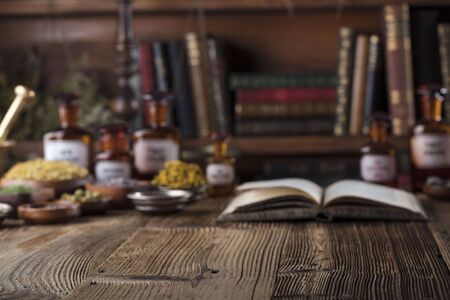 Alternative medicine. Wooden table, shallow depth of focus. Mortar, berries, flowers and herbs assorted in bowls.の写真素材