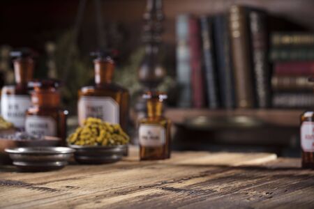 Alternative medicine. Wooden table, shallow depth of focus. Mortar, berries, flowers and herbs assorted in bowls.の写真素材