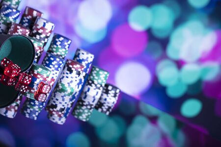 Casino thme. High contrast image of casino roulette, poker game, dice game, poker chips on a gaming table, all on colorful bokeh background.の写真素材