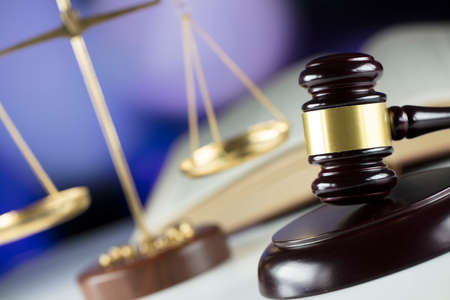 Gavel, book and scales on bokeh background.