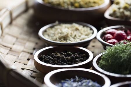 Natural medicine.  Herbs, berries and flowers in bowls on wooden table.の写真素材