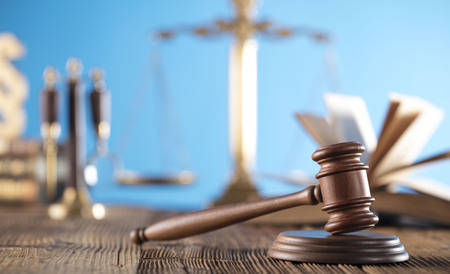 Judge concept. Mallet of the judge, justice scale and books on wooden desk and blue background.