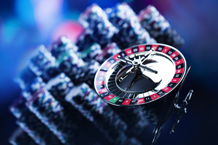 Casino theme. High contrast image of casino roulette, poker game, dice game, poker chips on a gaming table, all on colorful bokeh background. Place for typography and logo.の写真素材