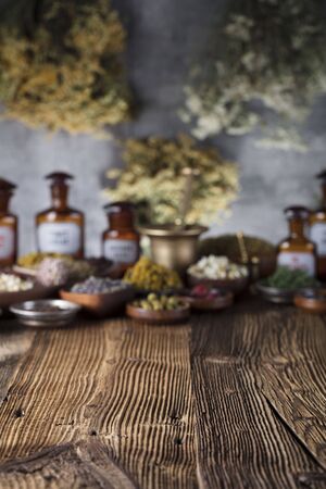Natural medicine background. Brass mortar, scale. Rustic table. Assorted dry herbs in bowls. Bokeh.の写真素材