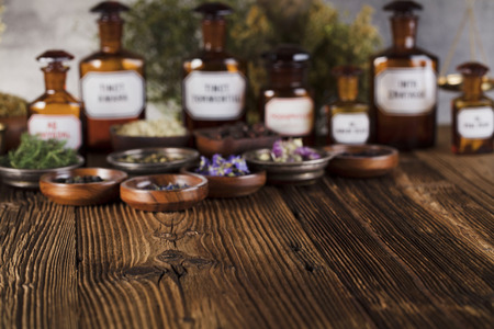 Natural medicine background. Brass mortar, scale. Rustic table. Assorted dry herbs in bowls. Bokeh.の写真素材