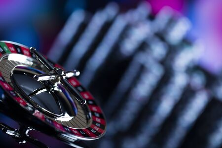 Casino theme. High contrast image of casino roulette and poker chips on a gaming table, all on...