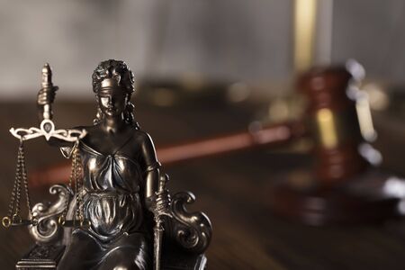 Statue of justice and  gavel of the judge on a stone background and rustic wooden table.の写真素材