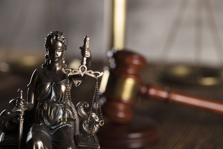 Statue of justice and  gavel of the judge on a stone background and rustic wooden table.の写真素材