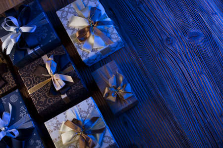 Presents in blue and gold aesthetics, rustic wooden table. Place for text.
