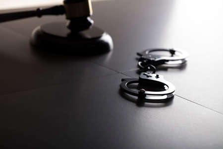 Criminal law concept. Cuffs and jugde gavel on stone background.の写真素材