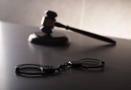 Criminal law concept. Cuffs and jugde gavel on stone background.の写真素材