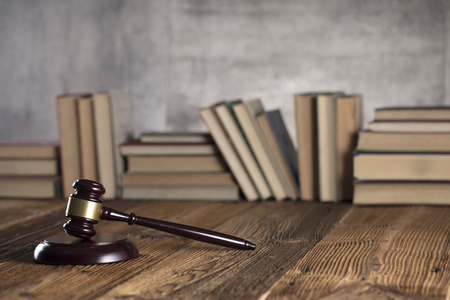 Gavel of judge on rustic wooden table. Bookshelf background.の写真素材