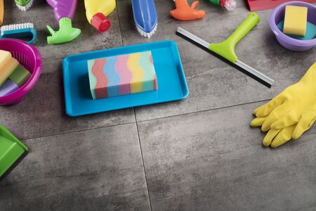 Spring cleaning concept. Colorful cleaning products on gray tiles. Place for typography.