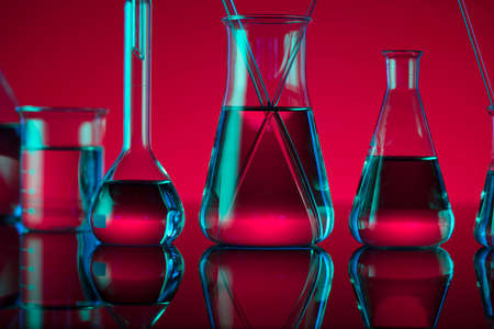 Chemical laboratory concept. Experiment with liquids. Red background.