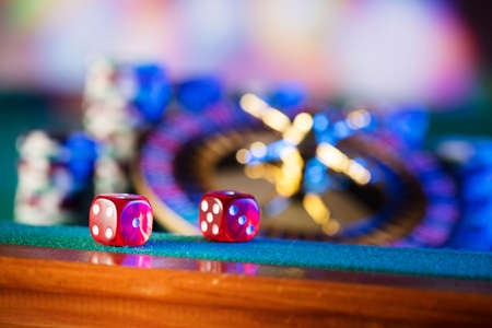 Gambling theme.  Dice, roulette wheel and poker chips  on color bokeh background.の写真素材