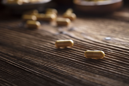 Curcuma capsules, turmeric roots and powder in bowls. Anti cancer medicine. Wooden tableの写真素材