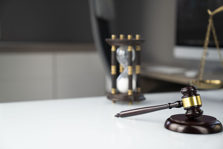 Law concept background. Gavel, scale and computer on the white glass table in the lawyer office.の写真素材