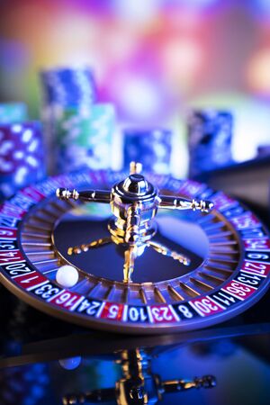 Gambling theme.  Roulette wheel and poker chips on color bokeh background.の写真素材