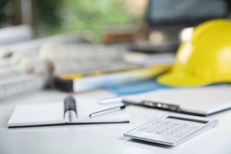 Contractor concept. Yellow hard hat, libella and plans on the white table.の写真素材