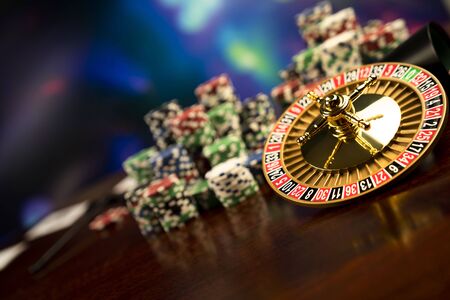 Casino theme.  Gambling games. Roulette, cards and poker chips on a colorful bokeh background.