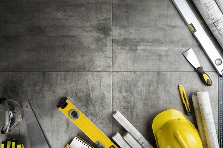 Contractor theme. Rolls with building projects, tools, crash helmet and spirit level on stone background.の写真素材