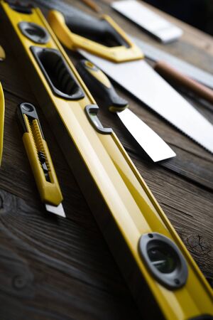 Contractor concept. Yellow hardhat, libella and other tools on the rustic wooden background.の写真素材
