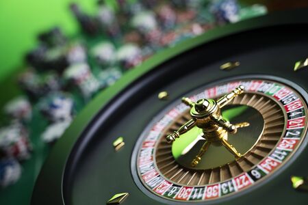 Casino theme, close up of roulette, red and black numbers. Stack of chips in the background.